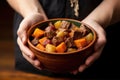 juicy beef stew in a bowl held by hand