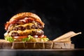 Juicy burger on the board, black background. Dark background, fast food. Traditional american food. Copy space.