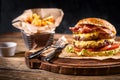 Juicy burger on the board, black background. Dark background, fast food. Traditional american food. Copy space.