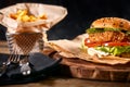 Juicy burger on the board, black background. Dark background, fast food. Traditional american food. Copy space.