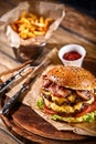 Juicy burger on the board, black background. Dark background, fast food. Traditional american food. Copy space.