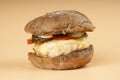 Juicy burger with dark bun closeup, cheeseburger with chicken cutlet, cheese and vegetables on beige background Royalty Free Stock Photo