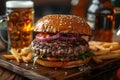 Juicy burger with fries on wooden tray, mug of beer in background Royalty Free Stock Photo