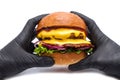 Juicy burger hamburger with cheese, onion, potatoes and salad on a white background in hands with gloves Royalty Free Stock Photo