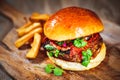 Juicy burger with pork ribs, tomato sauce, fresh vegetables and coriander on a wooden cutting board Royalty Free Stock Photo