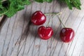 Juicy cherry berry near green mint leaves on vintage wooden background