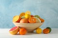 Juicy citrus fruits in bowl on wooden table against blue background Royalty Free Stock Photo