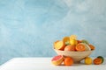 Juicy citrus fruits in bowl on wooden table against blue background Royalty Free Stock Photo