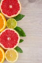 Juicy citrus fruits cut background mint leaf. Oranges, lemons, limes, grapefruit, mint leaves on a bright wooden background