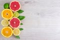 Juicy citrus fruits cut background mint leaf. Oranges, lemons, limes, grapefruit, mint leaves on a bright wooden background