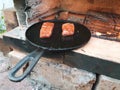 juicy cuts of meat are fried in a cast iron pan on burning coals in a barbecue oven