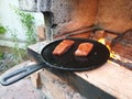 juicy cuts of meat are fried in a cast iron pan on burning coals in a barbecue oven