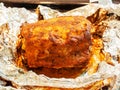 Juicy and delicious baked piece of pork with a golden crust on silver foil