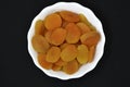 Juicy dried apricots in a white ceramic bowl. Dried apricot fruit halves without a stone