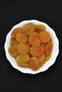 Juicy dried apricots in a white ceramic bowl. Dried apricot fruit halves without a stone