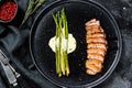 Juicy duck breast steaks with caramelized asparagus. Black background. Top view