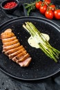 Juicy duck breast steaks with caramelized asparagus. Black background. Top view