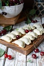 Juicy dumplings vareniki with fresh cherries on a wooden cutting board.