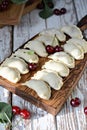 Juicy dumplings vareniki with fresh cherries on a wooden cutting board.