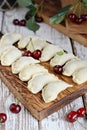 Juicy dumplings vareniki with fresh cherries on a wooden cutting board.
