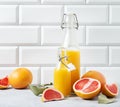 Juicy and fresh grapefruit and bottle juice on a blue table on  a white brick background. Concept healthy and diet  food. Front Royalty Free Stock Photo