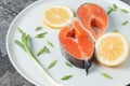 Juicy fresh salmon steak in a white plate with onion lemon and spices on a natural slate stone table close-up. Royalty Free Stock Photo