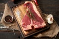 Juicy, fresh, seasoned t bone steak on a wooden cutting board on a piece of burlap with a sprig of rosemary on top, peppercorns Royalty Free Stock Photo