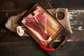 Juicy, fresh, seasoned t bone steak on a wooden cutting board on a piece of burlap with a sprig of rosemary on top, peppercorns Royalty Free Stock Photo