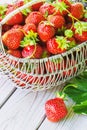 Juicy fresh strawberries in a basket on white wooden background, selective focus Royalty Free Stock Photo