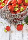 Juicy fresh strawberries in a basket on white wooden background, selective focus Royalty Free Stock Photo