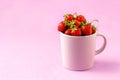 Juicy fresh strawberries in a cup on a pink background