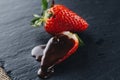 Juicy fresh strawberries drenched with chocolate sauce on a gray stone background