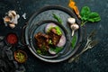 Juicy fried pork steak with spices on a black stone plate. Royalty Free Stock Photo