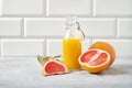 Juicy grapefruit and bottle juice on a blue table on  a white brick background. Front view and copy space Royalty Free Stock Photo