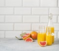 Juicy grapefruit and bottled juice on a blue table on  a white brick background. Front view and copy space Royalty Free Stock Photo