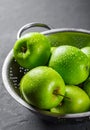 Juicy green apple in stainless steel colander on Dark grey black slate background Royalty Free Stock Photo