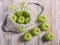 Juicy green apples and cotton string mesh bag on a wooden table. Top view Royalty Free Stock Photo