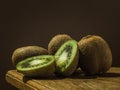 Juicy green kiwi, on a wooden table, with a dark background, soft light. Imitation of a Dutch kitchen still life. Mono food