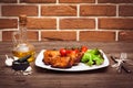 Juicy grilled pork fillet served with cherry tomatoes branch and lettuce on white plate. Background: brick wall. Close-up. Horizon Royalty Free Stock Photo