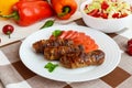 Juicy grilled rolls of minced meat wrapped in bacon with fresh tomato and a light salad of Chinese cabbage Royalty Free Stock Photo