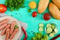 Juicy grilled sausages, fresh vegetables, greens and crispy buns on a bright background. Royalty Free Stock Photo