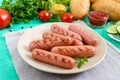 Juicy grilled sausages, fresh vegetables, greens and crispy buns on a bright background. Royalty Free Stock Photo