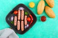 Juicy grilled sausages on grill pan with vegetables and crispy bun. Top view. Royalty Free Stock Photo