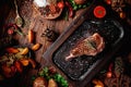 Juicy grilled steak on the bone decorated rosemary on dark board on dark wooden background Royalty Free Stock Photo