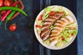 Juicy home made sausage with a light spring salad of fresh vegetables on a black wooden background. A traditional Easter dish. Royalty Free Stock Photo