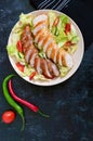 Juicy home made sausage with a light spring salad of fresh vegetables on a black wooden background. Royalty Free Stock Photo