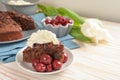 Juicy homemade chocolate cake with morello cherries and whipped cream, some tulip flowers and a blue napkin on a bright wooden Royalty Free Stock Photo