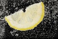 Juicy lemon slice in soda water against black background, closeup Royalty Free Stock Photo