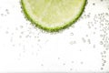 Juicy lime slice in soda water against white background, closeup. Space for text Royalty Free Stock Photo