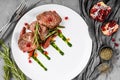 Juicy medium beef fillet steaks mignon with green beans, pomegranate and sauce in plate on grey background